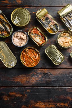 Farklı türde deniz ürünleri olan balıklar için teneke kutular, Saury, uskumru, sprat, sardalya, sardalya, sardalya, kalamar, mürekkep balığı, ton balığı ile açılmış ve kapanmış konserve kutuları, üzerinde eski ahşap düz masa üstü yazı için üst görünüm alanı.