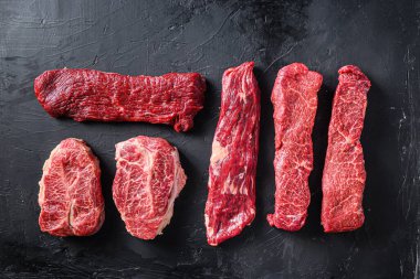 Çiğ organik et Top Blade bifteği pala ve Denver bifteği yanında, alternatif biftek kesimi ya da Avustralya wagyu istiridye bıçağı siyah arka planda üst görünüm için metin alanı.