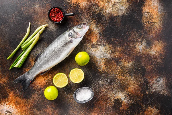 Rauwe zeebaars met specerijen en kruiden ingrediënten over donkere rustieke achtergrond bovenaanzicht ruimte voor tekst. — Stockfoto
