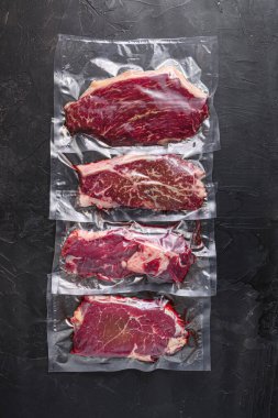 Süpürge paketlenmiş organik sığır eti alternatif kesimler: üst bıçak, kıç, picanha, chuck roll biftekleri, siyah desenli arka plan, üst görünüm