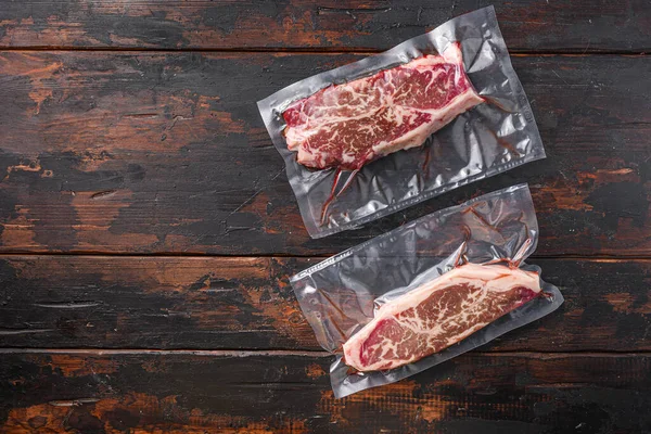 Top blade beef steak Vacuum packed meat on dark old wooden table, top view with space for text