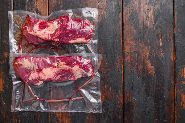 Chuck roll beef steak Vacuum packed meat on dark old wooden table, top view with space for text