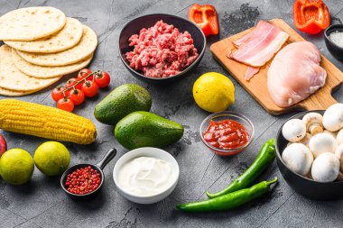 Tako malzemeleri sebzeli, tavuklu, domuz etli, mısırlı, mantarlı ve gri arka planda ev yapımı yemekler.