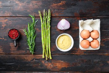 Taze kuşkonmaz yumurtaları ve dijon hardallı Fransız sos malzemeleri, koyu ahşap arka planda soğan taragonu, üst manzara.