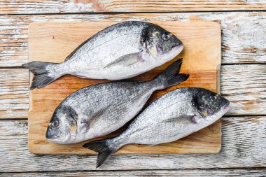 Çiğ dorada ya da Choppong tahtasında çipura beyaz ahşap masa manzarası üzerinde