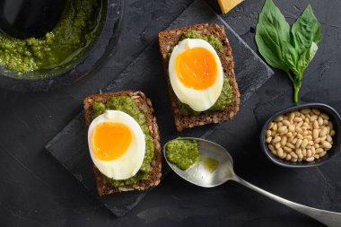 İtalyan kahvaltısında yeşil fesleğen soslu ev yapımı panini ekmeği. İçindekiler siyah taş beton masa yüzeyinde yeşil pesto. Yakın plan..