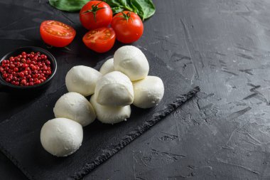 Taze kiraz domatesleri, fesleğen yaprağı, siyah tahta üzerinde mozzarella peyniri sağlıklı İtalyan geleneksel Caprese salatası malzemeleri. Organik Akdeniz gıda kavramı, metin yatay için seçici odak alanı.