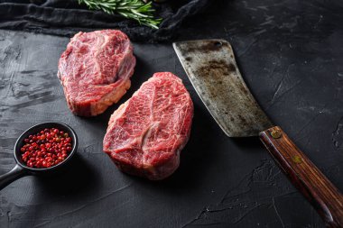 Çiğ üst bıçak organik et biçer kasap akıllı bıçak bbq veya gtrill üst görünüm siyah taş arka plan kapalı seçici odaklı.