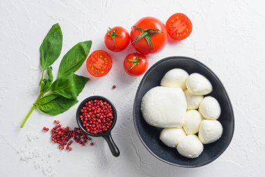Çiğ Mozzarella peynirli toplar taze fesleğen yaprakları ve kiraz domatesleri, malzemeler, beyaz arka planda..