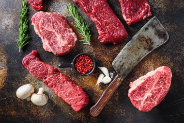 Farklı türde çiğ sığır eti bifteği, kasap bıçağı ile rustik metall arka plan düz yatay görünüm.