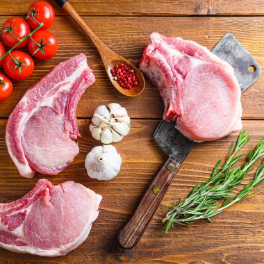 Çiğ domuz pirzolası, otlu ve baharatlı, ahşap arka planda Amerikan satırı yazılı. Kare.