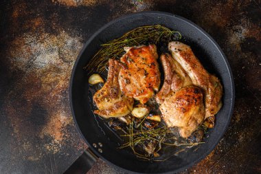 Izgarada organik domuz pirzolası, kemiğe otlar, ızgarada kızartma tavası, dumanla sıcak, ateşten sıcak yağ, en tepedeki pişirme kemiği, baharatlı, taşralı metal arka planda yakın plan.