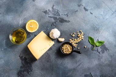 Pesto genovese sosu için İtalyan malzemeleri, sağlıklı besin fesleğeni, zeytinyağı, parmesan, sarımsak, çam fıstığı. Yukarıdan kopyalanmış boşluklu gri bir arkaplan üzerinde konsept.