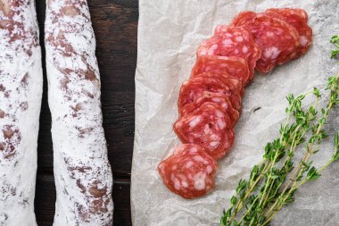 Fuet, kuru sosis dilimlere kesilmiş koyu ahşap arka plan, üst görünüm.