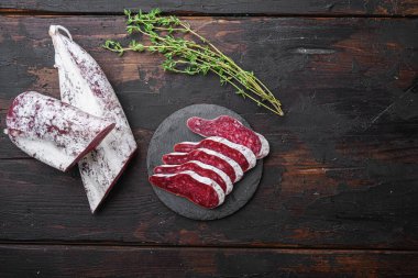 Longaniza, kurutulmuş geleneksel sosis. Koyu ahşap arka planda dilimler halinde kesilmiş ve metin için yer var..