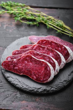 Longaniza, kurutulmuş geleneksel sosis eski ahşap masada dilimlenmiş..