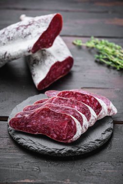 Longaniza, kurutulmuş geleneksel sosis eski ahşap masada dilimlenmiş..