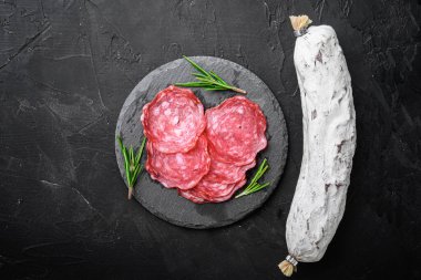 Kuru, bütün ve dilimler siyah desenli yüzey üzerinde salchichon sosisi, üst görünüm metin için boşluk.