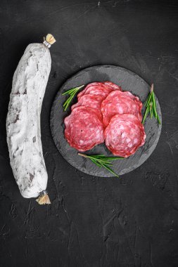 Kurumuş, bütün ve dilimlenmiş siyah arka planda salchichon sosisi, düz uzanmış.