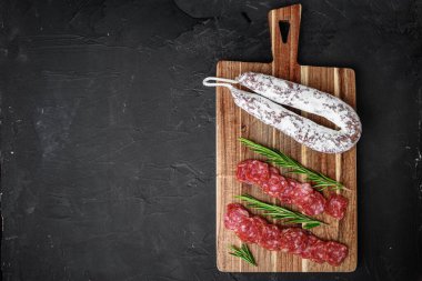 Fuet salam sosis dilimlenmiş ve tüm sosis siyah desenli yüzey üzerinde metin için yer var..