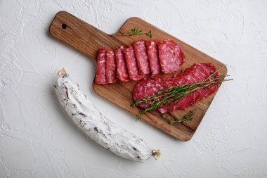 Salchichon bütün ve dilimlenmiş kesikler, İspanyol sosisi beyaz desenli arka plan, üst görünüm.