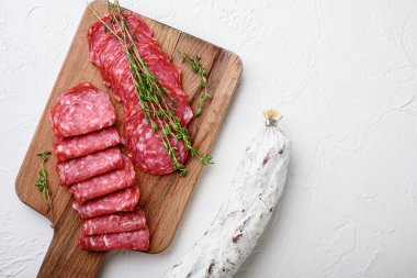 Salchichon bütün ve dilimlenmiş kesikler, beyaz yüzeyde İspanyol sosisi, fotokopi alanı ile üst görünüm.