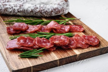 Beyaz desenli arka planda bütün ve dilimlenmiş İspanyol kuru sosisi..