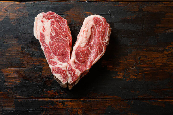 Love Raw Chuck Tenders steak on vintage dark wood table Organic beef. Black  Top view.  Space for text.