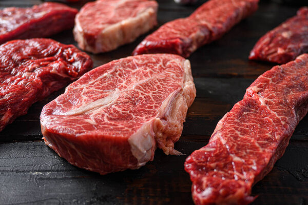 Alternative black angus cut top blade steak near denver steak close up in front of other cuts in butchery on old wood table side view selective focus.