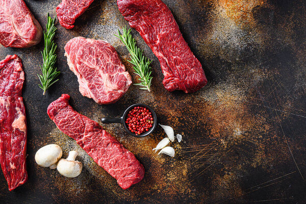 Variety,  of raw beef steaks  flap flank Steak, machete steak or skirt cut, Top blade or flat iron beef and tri tip, triangle roast with denver cut top view over old rustic metal surface  space for text.