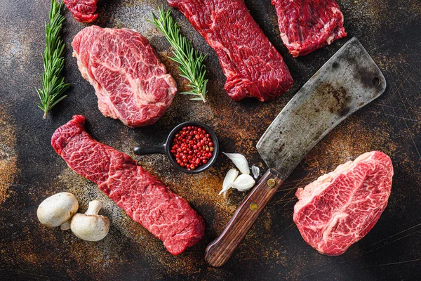 Farklı türde çiğ sığır eti bifteği, kasap bıçağı ile rustik metall arka plan düz yatay görünüm.