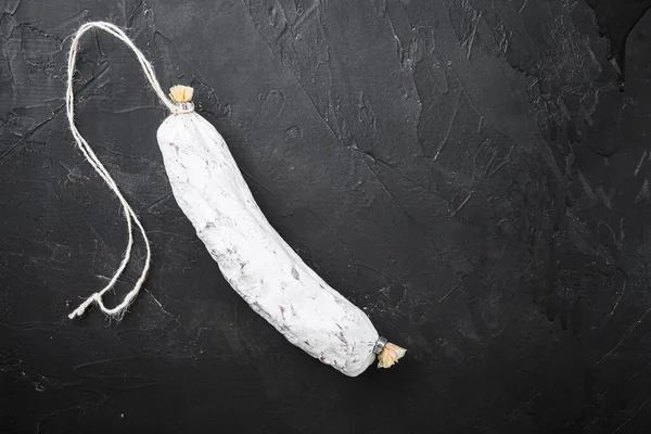 Salchichon, siyah arkaplanda İspanyol salamı sosisi, üst görünümde metin için boşluk.