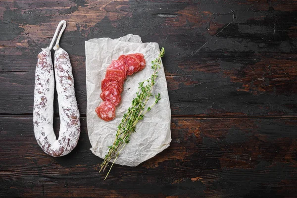 Fuet, dry cured sausage cut to slices on old wooden table, flat lay with copy space.