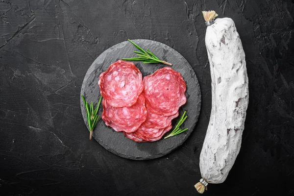 Kuru, bütün ve dilimler siyah desenli yüzey üzerinde salchichon sosisi, üst görünüm metin için boşluk.