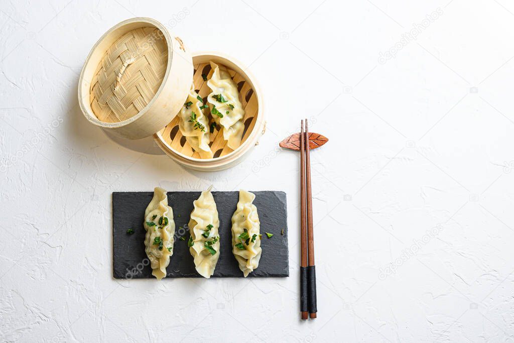 steamed dumpling or Japanese gyoza, dumplings snack  in traditional wooden steamer and black stone slate on white texture stone background top view space for text