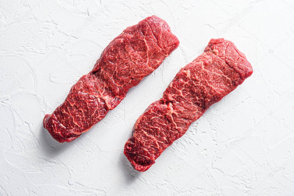 Raw set of denver steak on a white stone background top view.