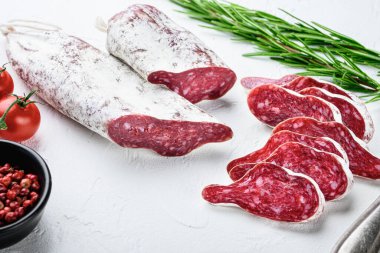 Dilimlenmiş longaniza, kurutulmuş İspanyol sosisi otlar ve baharatlar beyaz desenli arka planda.
