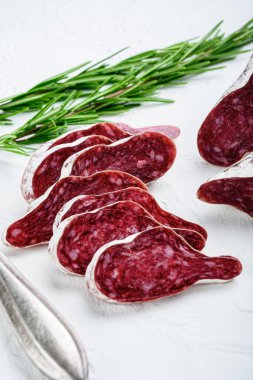 Dilimlenmiş longaniza, kurutulmuş İspanyol sosisi otlar ve baharatlar beyaz desenli arka planda.