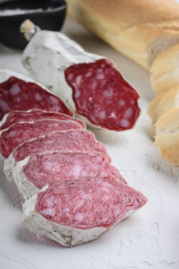 İspanyol salcicon dilimleri panini ile ve beyaz dokulu arka planda otlar.