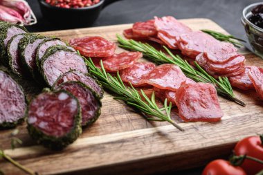 İspanyol fuet salam sosisi dilimleri siyah desenli arka planda.