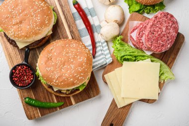 Sığır burger, patates kızartması ve beyaz arka planda ham malzemeler..