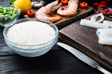Siyah ahşap masa üzerinde İspanyol deniz ürünleri paella parçaları, yemek fotoğrafı..