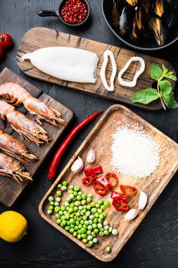 Kral karidesli, midyeli ve kalamarlı taze pişmemiş paella malzemeleri. Siyah desenli arka plan, üst manzara, yemek fotoğrafı..