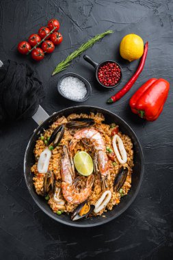 Paella geleneksel İspanyol yemeği kızartma tavasında servis edilir, siyah desenli yüzey, üst manzara, yemek fotoğrafı..