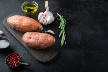 Siyah zemin üzerinde otlar ve baharatlarla, kopyalanmış tatlı patatesler.