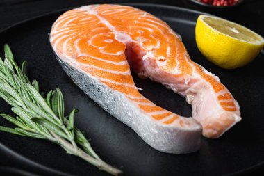 Siyah ahşap yüzeyde otlu somon bifteği..