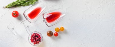 Beyaz beton masa manzarasında ızgara yapmak için otların yanında iki kadeh kırmızı şarap. Büyük afiş boyutunda. Metin için boşluk