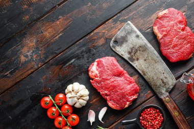 Kalça bifteği organik et, çiğ mermer biftek, eski kasap bıçağı satırı ve baharatlar koyu ahşap kırsal masa, metin için üst görünüm