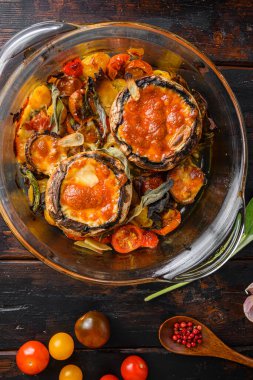 Portobello mantarı, çedar peyniri, vişneli domates ve adaçayı eski ahşap arka plan manzarasında cam kapta pişirilir.