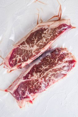 Süpürge paketlenmiş organik et bifteği beyaz beton desenli arka plan, üst manzara